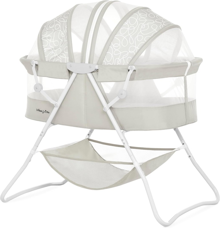 light gray dream on me karley folding bassinet with a mesh canopy and a storage basket underneath