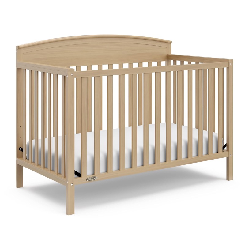 light driftwood graco benton convertible crib with slatted sides and a curved headboard