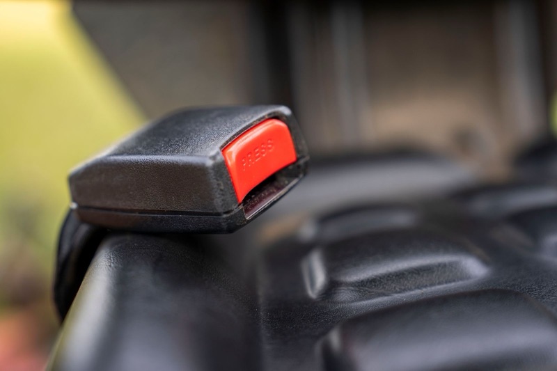 close view of a black car seat belt buckle with a red release button