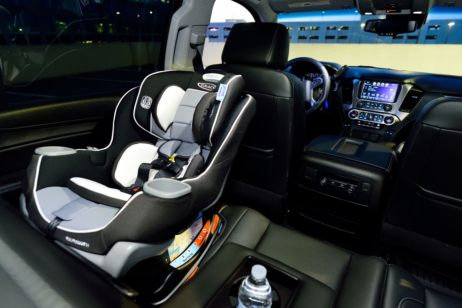 gray and black convertible car seat installed in the back seat of a car, seen from the open door