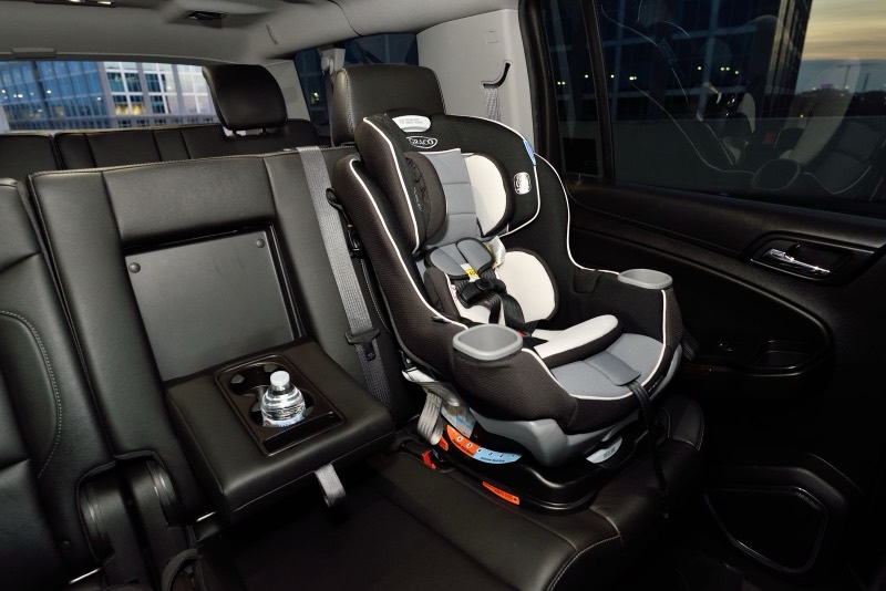 gray and black convertible car seat installed in the back seat of a car with dark leather seats