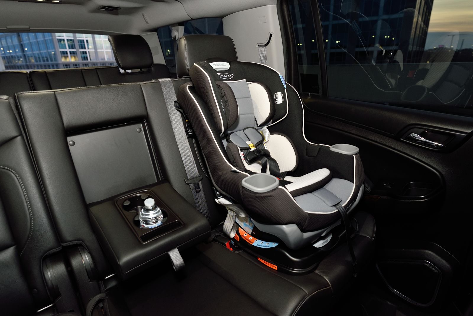 gray and black convertible car seat installed in the back seat of a car with dark leather seats