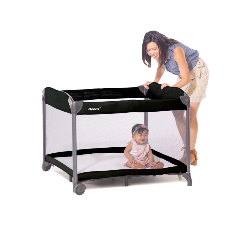 black joovy room2 square play yard with large mesh windows and a woman leaning over it