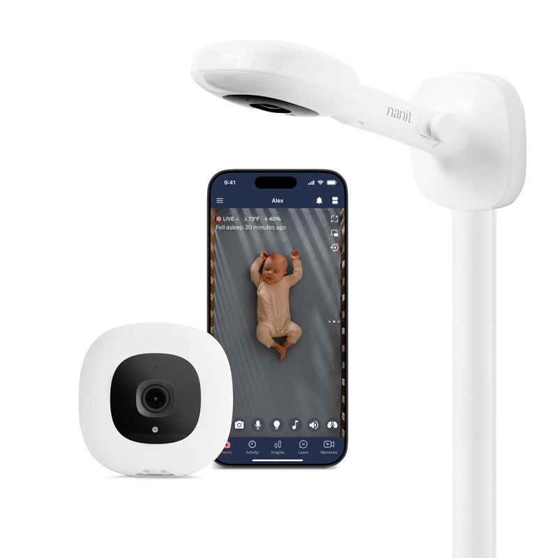 nanit pro camera on a white overhead wall mount next to a phone showing a baby in the nanit app